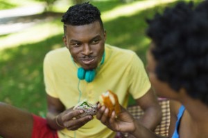 Young couple in park picnicing on sandwiches